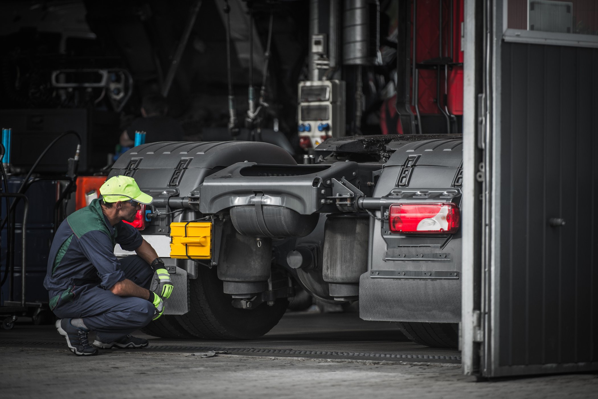 Caucasian Truck Mechanic Inspecting Truck in the Garage